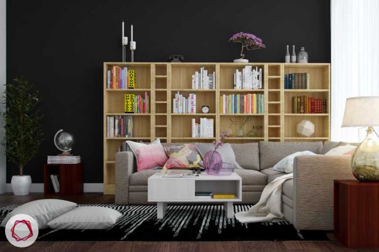 Neutral themed home library with large bookshelf and L shaped sofa.