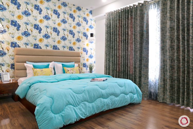 a-bedroom-with-a-blue-comforter-and-floral-wallpaper