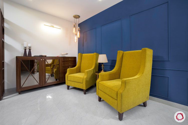 seating area-yellow wingback chair-blue accent wall-pendant light-wooden console