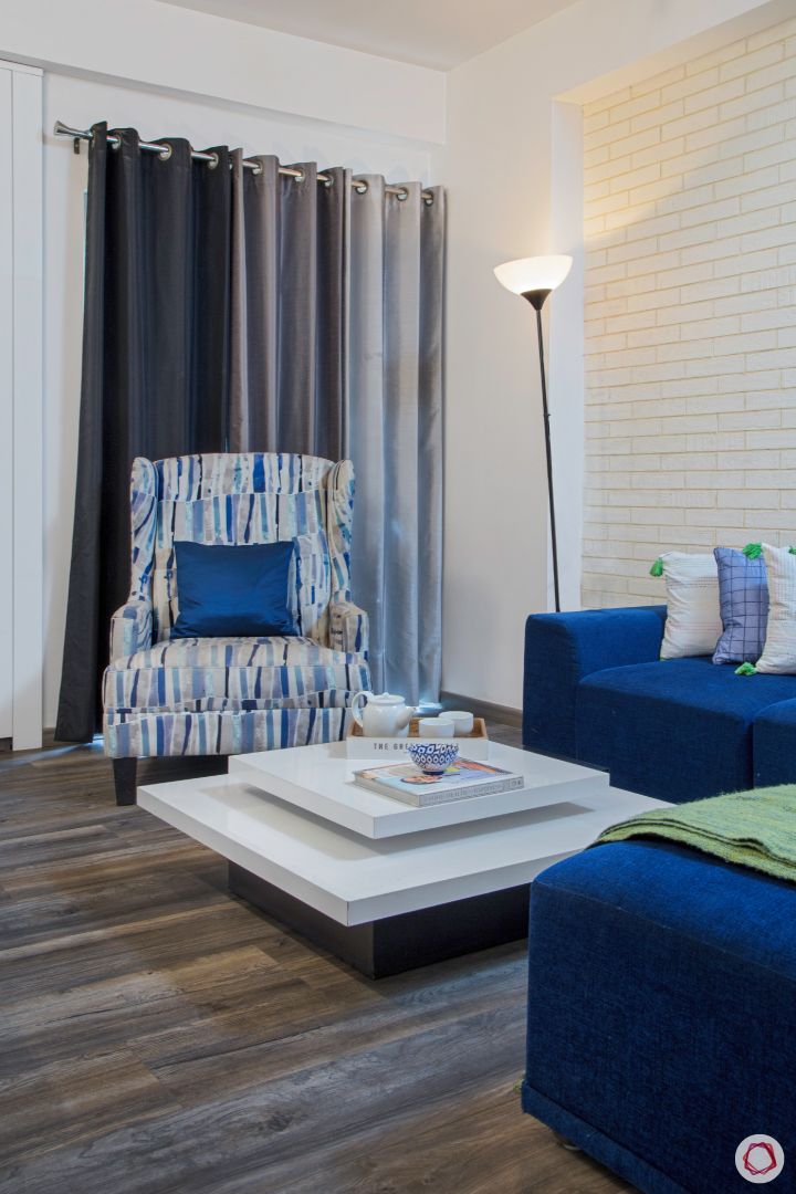 New house design-entertainment room-blue sofa-white exposed brick accent wall-floor lamp-coffee table