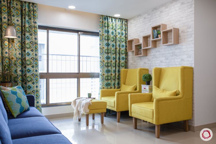 godrej homes-mumbai home-living room-yellow chairs-display shelves-exposed brick wallpaper-printed curtains