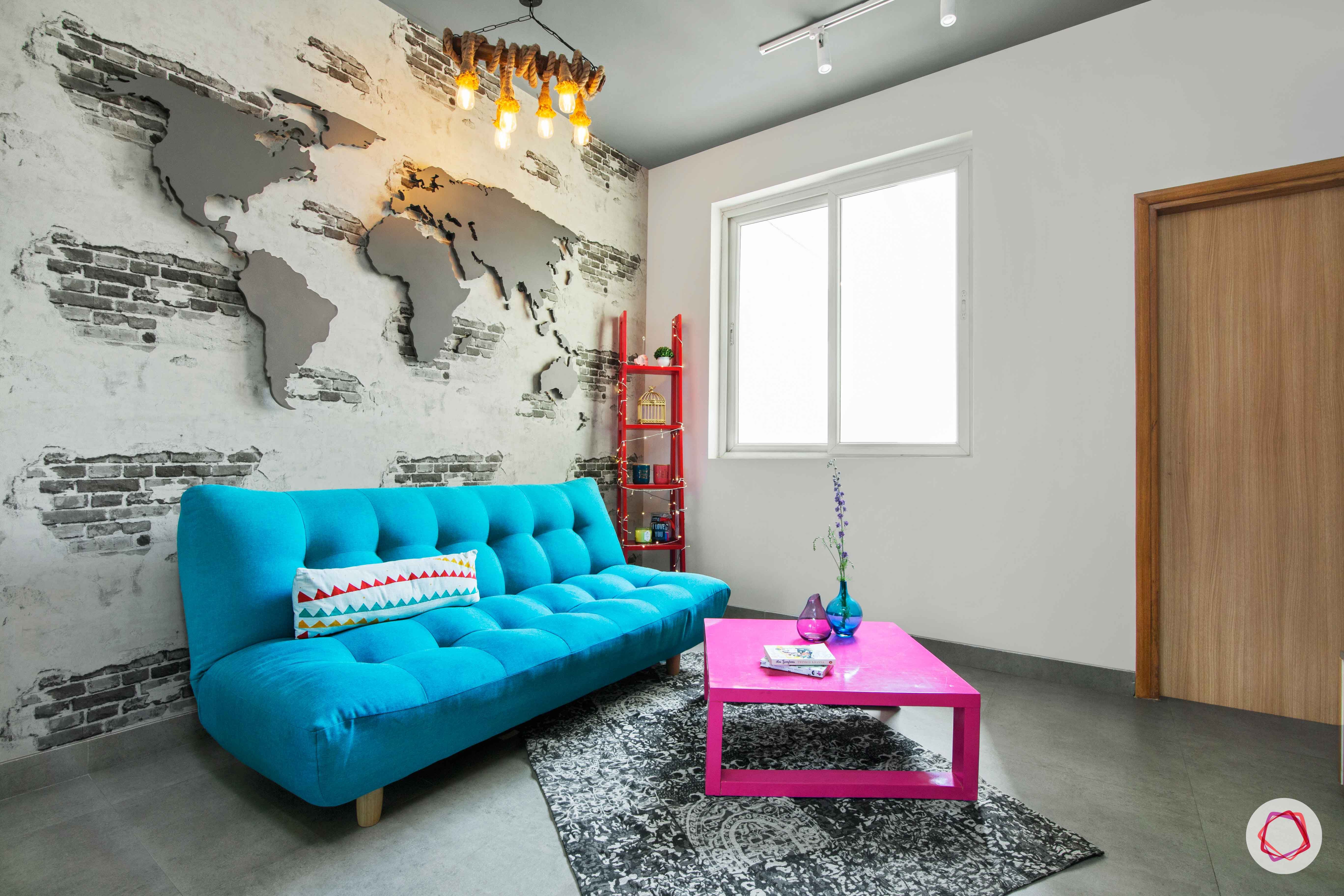tdi ourania_blue sofa cum bed_pink table_exposed brick wall