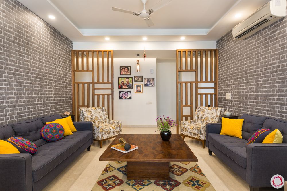 4 bhk apartment-living room-hardwood partitions-grey brick wall-grey sofa designs
