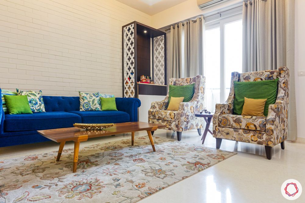 3 bhk interior design-living room-blue sofa-jaali pooja unit-white exposed brick wallpaper-centre table