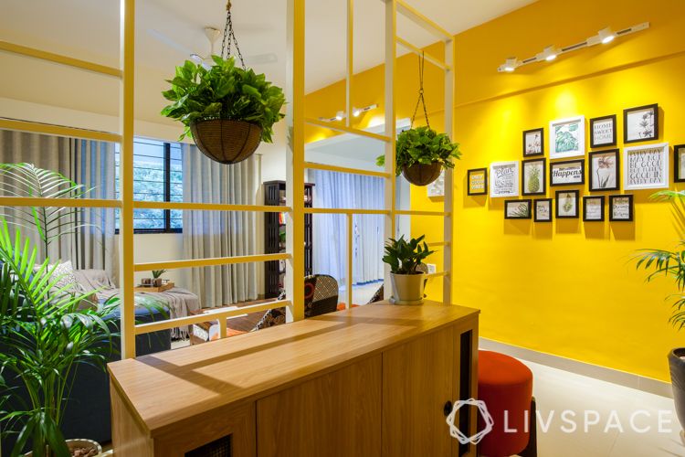 small house interior design-yellow wall-red ottoman-track lights-framed wall