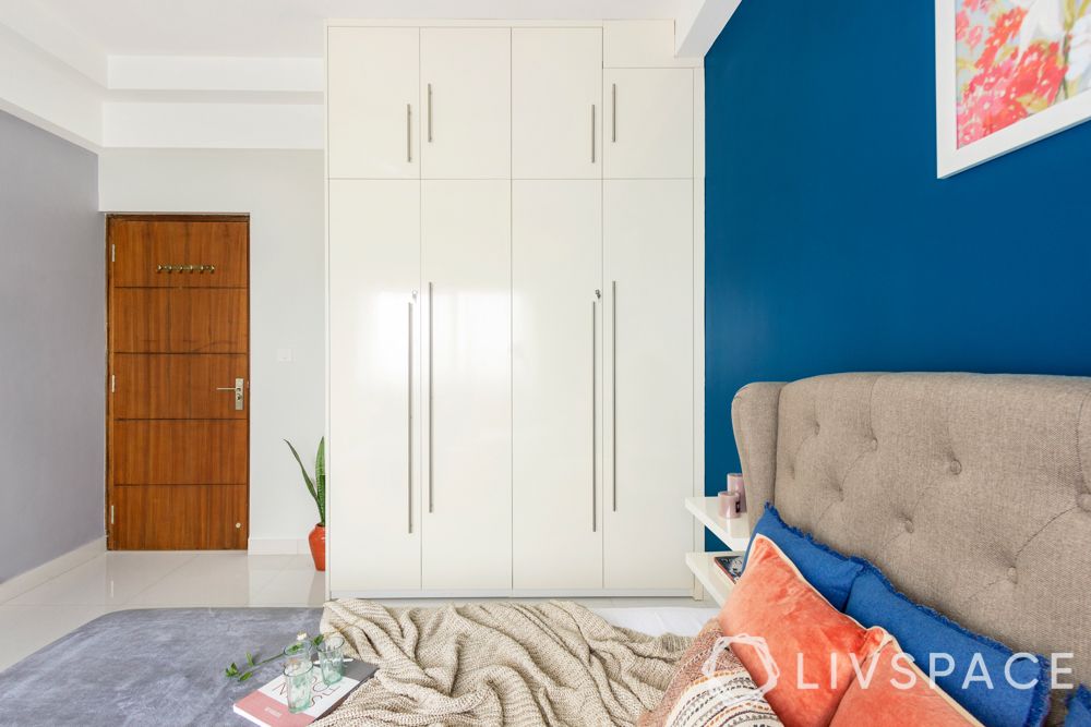 interiors in bangalore-blue painted walls-wall art-upholstered bed-white wardrobes