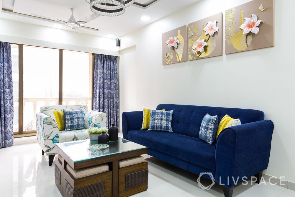 clean white walls-blue sofa-wall art-coffee table-blue curtains-printed armchair