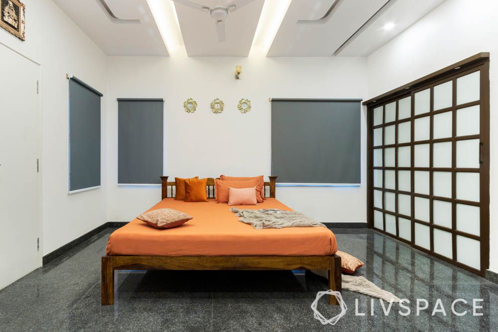 villa design-master bedroom-wooden bed-orange bedding-wooden rafters door-pop false ceiling

