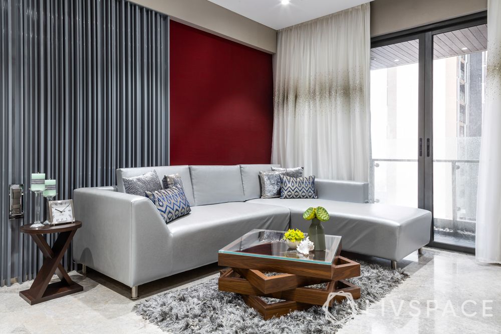 Compact home-living room-silver sofa-maroon accent wall-centre table-rug