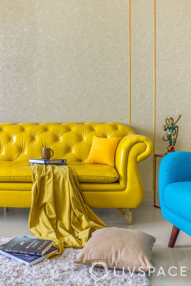 yellow tufted sofa-gold trims on wall
