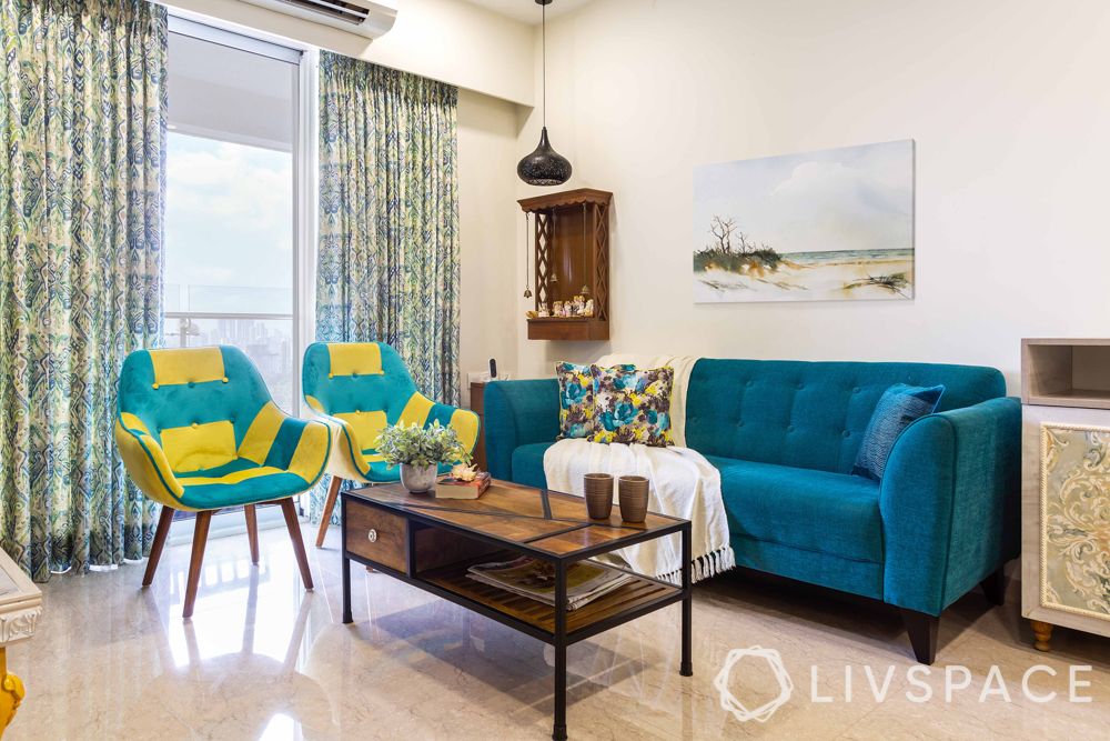 livspacehomes-low-budget-house-living-room-teal-sofa-accent-chairs-centre-table