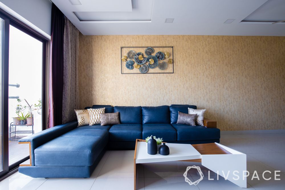 2bhk-in-Pune-living-room-blue-sofa-gold-wallpaper-metal-art
