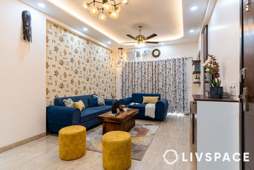 interior-design-cost-in-gurgaon-for-living-room-with-blue-sofa-yellow-pouffes-accent-wall-false-ceiling