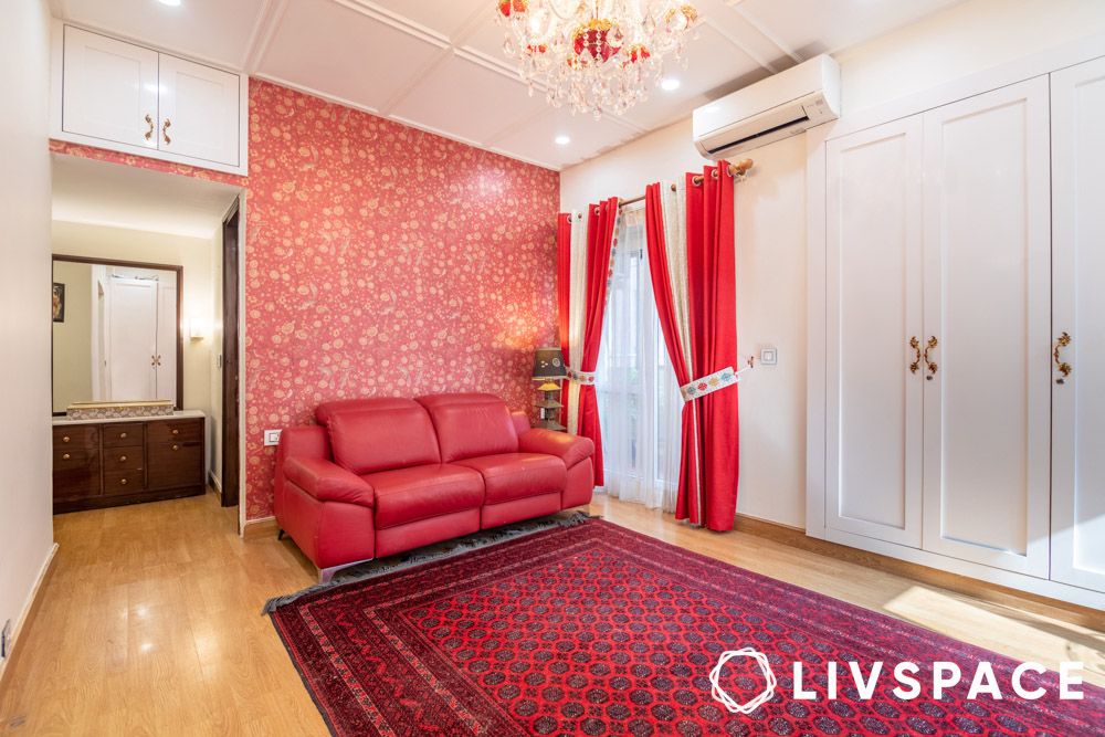 lounge-in-master-bedroom-with-red-sabyasachi-wallpaper-chandelier-carpet.