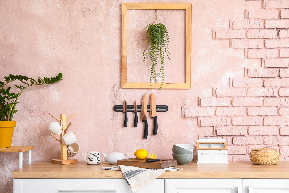 magnetic board for knives hanging in a pink coloured kitchen