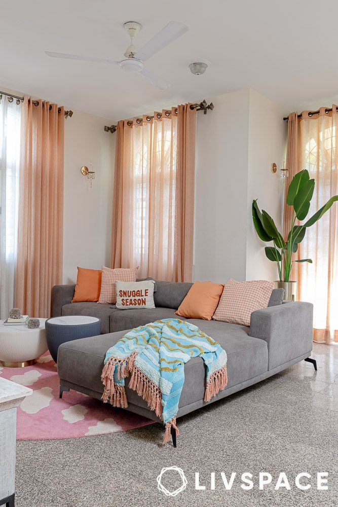 a grey couch with pastel coloured cushions and throw