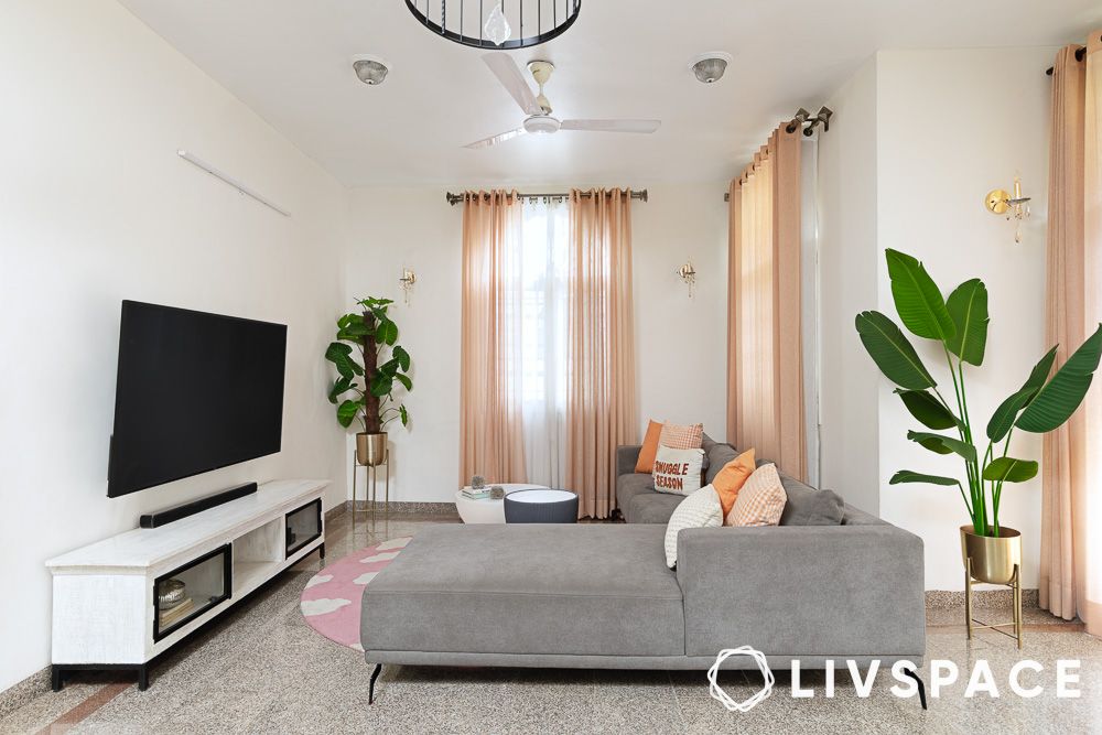 a grey l shaped couch and tv unit in a white living room