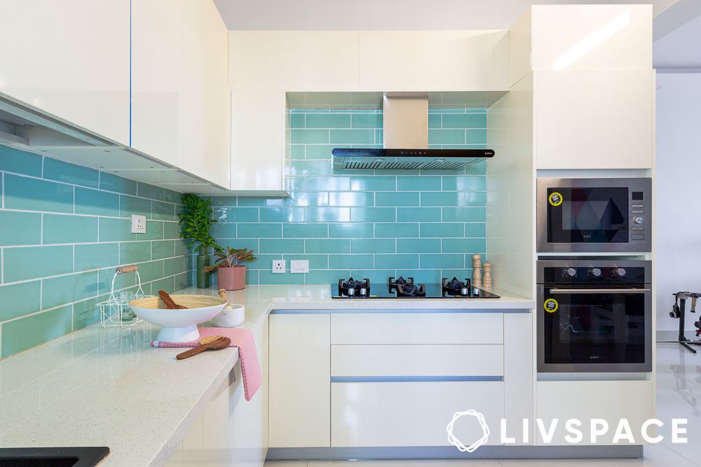Glossy white L shape modular kitchen design with a pop of blue