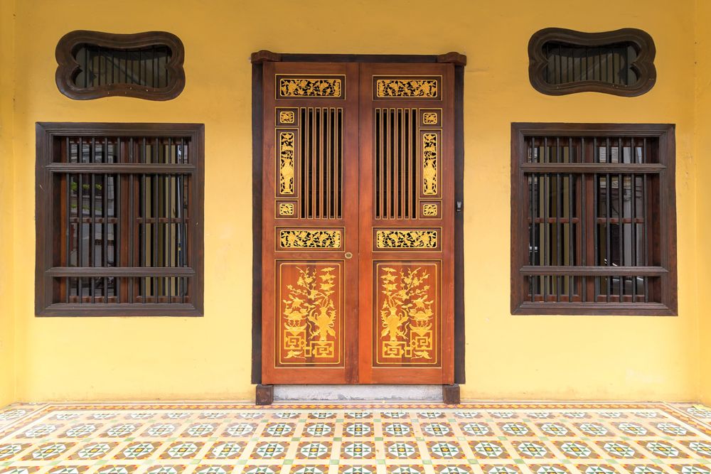 peranakan floor tiles-wooden carvings on door-yellow wall 