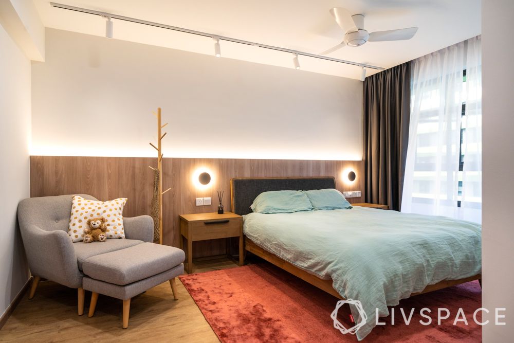 modern-house-bedroom-wooden-flooring-grey-armchair-blue-bed-linen-red-rug