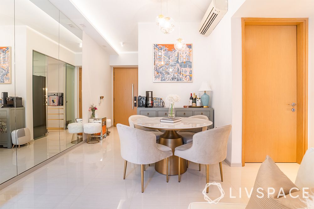 small-condo-interior-design-dining-area-mirror-wall-dining-table-grey-chairs-metal-accents